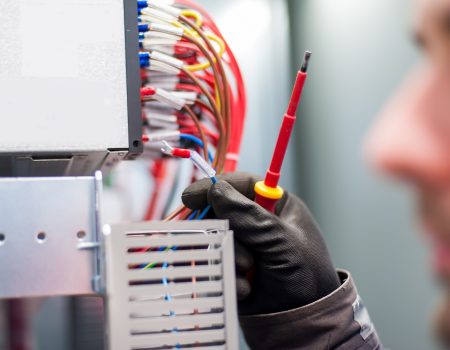 Closeup of electrician engineer works with electric cable wires of fuse switch box. Electrical equipment